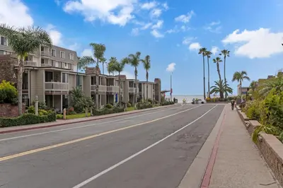 an empty street with palm trees and condos at North Coast C106 in Oceanside