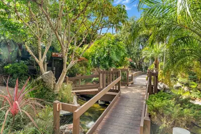 a wooden bridge over a stream in a garden at North Coast C106 in Oceanside