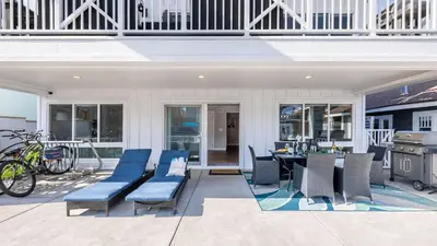an outdoor patio with blue chairs and a table at Ocean Breeze I by AvantStay Steps to the Beach in Newport Beach