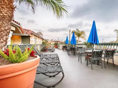 a patio with tables and chairs and blue umbrellas at Laguna Brisas - A Beach Hotel in Laguna Beach