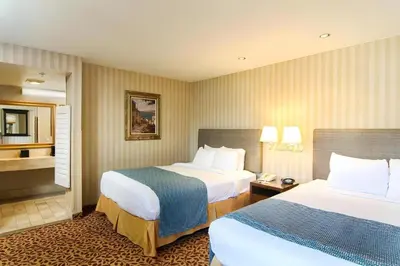 a hotel room with two beds and a bathroom at Laguna Brisas - A Beach Hotel in Laguna Beach