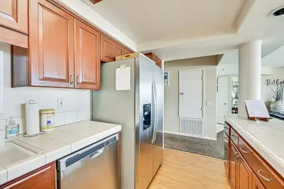 a kitchen with wooden cabinets and a stainless steel refrigerator at Ocean-View Imperial Beach Condo with Community Perks in Imperial Beach