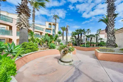 a courtyard with palm trees and a building at Ocean-View Imperial Beach Condo with Community Perks in Imperial Beach