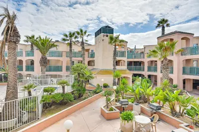 an exterior view of a building with palm trees at Ocean-View Imperial Beach Condo with Community Perks in Imperial Beach