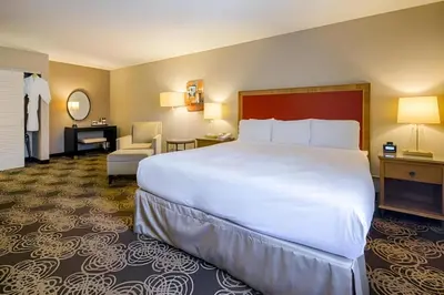 a hotel room with a large white bed and a chair at Hotel San Diego-Rancho Bernardo in Rancho Bernardo