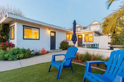 two blue chairs sitting on the grass in front of a house at Pet Friendly Beach Bungalow, Close to Beach in Carlsbad