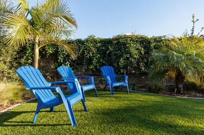 three blue chairs sitting around a table in the grass at Pet Friendly Beach Bungalow, Close to Beach in Carlsbad