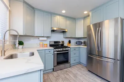 a kitchen with blue cabinets and a stainless steel refrigerator at Pet Friendly Beach Bungalow, Close to Beach in Carlsbad
