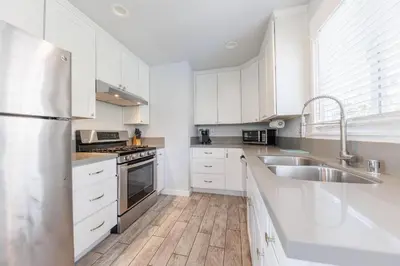 a kitchen with white cabinets and a stainless steel sink at Walk to Beach, Outdoor Living, Pet-Friendly! in Carlsbad