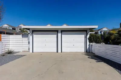 a white garage with two doors on a driveway at Walk to Beach, Outdoor Living, Pet-Friendly! in Carlsbad