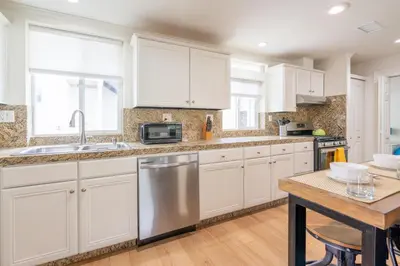 a kitchen with white cabinets and a stainless steel dishwasher at CBS-1236 - Sensational Summit Sunsets in Cardiff-by-the-Sea