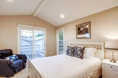 a bedroom with a bed and a chair and a window at Villa Solamar-Sunset Cliffs Spectacular in San Diego