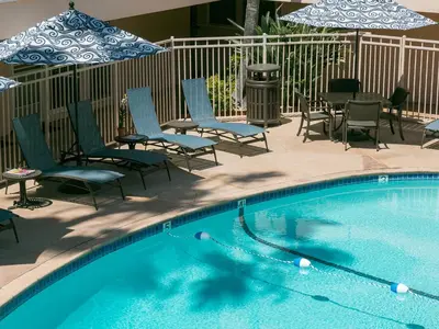 a swimming pool with chairs and tables and umbrellas at La Jolla Riviera Inn in San Diego