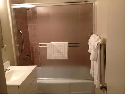 a bathroom with a sink and a shower with towels at La Jolla Riviera Inn in San Diego