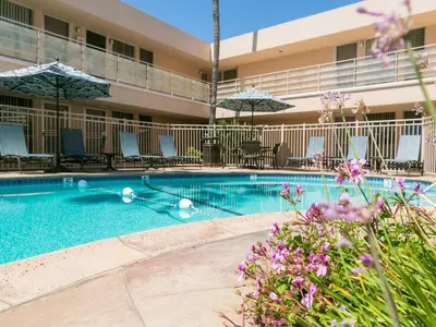 a pool at a hotel with chairs and umbrellas at La Jolla Riviera Inn in San Diego