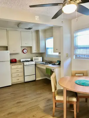 a kitchen with white cabinets and a table and a dining room at La Jolla Riviera Inn in San Diego