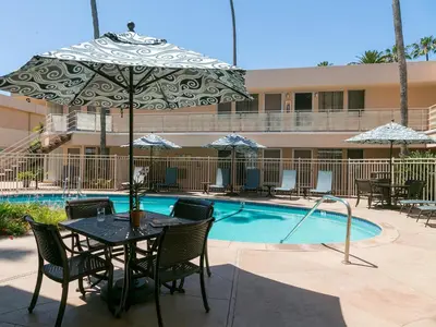 a table with an umbrella next to a swimming pool at La Jolla Riviera Inn in San Diego
