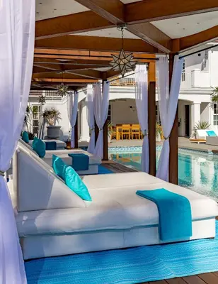 a bed with blue pillows next to a swimming pool at Cypress Cabana Chateau Luxury Vacation Villa in San Diego