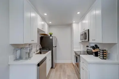 a white kitchen with white cabinets and a refrigerator at 3 Mi to La Jolla Shores Relaxing Resort Retreat! in San Diego