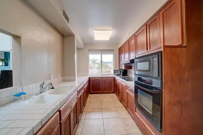a large kitchen with wooden cabinets and a sink at 3 Mi to La Jolla Shores Relaxing Resort Retreat! in San Diego