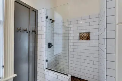 a white tiled shower with a mirror in a bathroom at The Stanton Residence - Chic and Cozy Classic near Downtown in San Diego