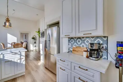 a kitchen with white cabinets and a stainless steel refrigerator at The Stanton Residence - Chic and Cozy Classic near Downtown in San Diego