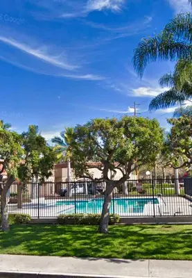 a pool in a park with trees and a fence at Cali Condo+BBQ+MemoryFoamBeds+12min to Beach in San Juan Capistrano