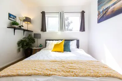 a bedroom with a large white bed with yellow pillows at Cali Condo+BBQ+MemoryFoamBeds+12min to Beach in San Juan Capistrano