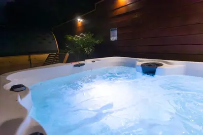 a bath tub filled with blue water at night at Private House 3 min to beach large backyard Spa Sauna BBQ ! in San Juan Capistrano