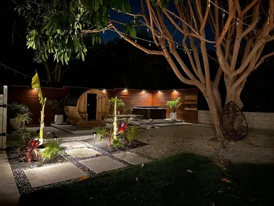 a garden at night with a table and a tree at Private House 3 min to beach large backyard Spa Sauna BBQ ! in San Juan Capistrano