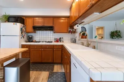 a kitchen with wooden cabinets and a white refrigerator at Private House 3 min to beach large backyard Spa Sauna BBQ ! in San Juan Capistrano