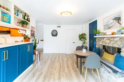 a kitchen with blue cabinets and a table and a fireplace at Private House 3 min to beach large backyard Spa Sauna BBQ ! in San Juan Capistrano