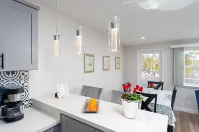 a kitchen with white counters and a counter top with red flowers at 100 PERCENT NEW STUNNING HUGE HOME, GARDEN BEACH, RESERVED Parking in Laguna Beach