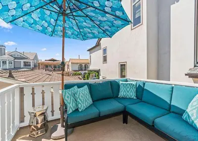 a blue couch on a balcony with an umbrella at Balboa Paradise - Renovated Coastal Haven in Newport Beach