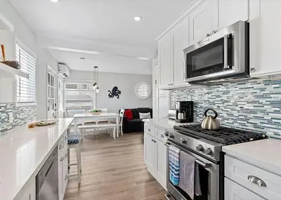 a kitchen with white cabinets and a stove top oven at Balboa Paradise - Renovated Coastal Haven in Newport Beach