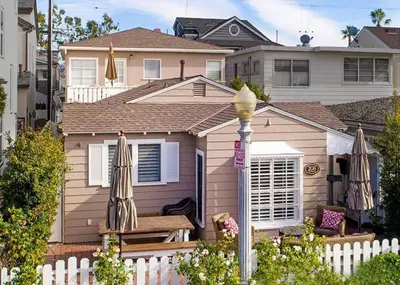 a house with a white fence and a bench and umbrellas at Balboa Paradise - Renovated Coastal Haven in Newport Beach