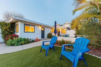 two blue chairs sitting in the grass in front of a house at Charming Beach Bungalows - 4BR, Sleeps 10, Pets OK in Carlsbad