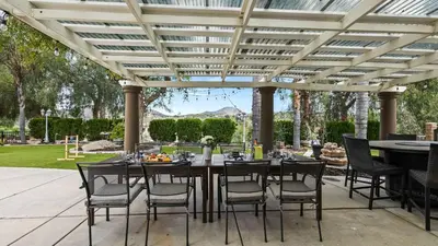 a patio with a table and chairs under a pergola at Breathtaking Meadows by AvantStay Temecula Group Retreat Pool Pickleball Firepit Hot Tub in Temecula