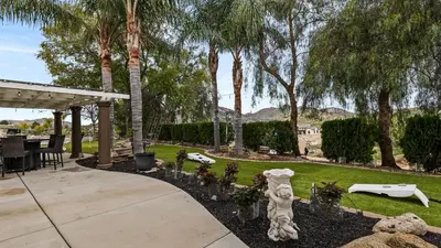 a patio with a yard with palm trees at Breathtaking Meadows by AvantStay Temecula Group Retreat Pool Pickleball Firepit Hot Tub in Temecula