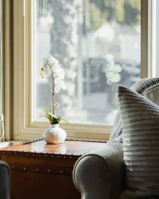 a vase with flowers on a table next to a window at Casa Flora -2BR- FREE Parking in Little Italy! in San Diego