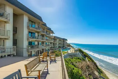 a hotel balcony with tables and chairs and the ocean at Del Mar Gem condo in Solana Beach