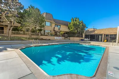 a swimming pool with blue water in front of a building at Del Mar Gem condo in Solana Beach