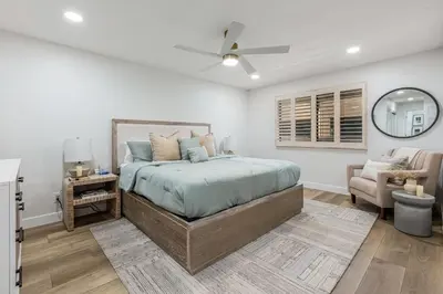 a bedroom with a bed with a fan and a chair at Del Mar Gem condo in Solana Beach