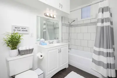 a white bathroom with a tub and a sink and a shower at 3 Bedroom 2 Bath House with Parking - 10 Guests in San Diego