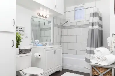 a white bathroom with a tub and a toilet and a sink at 3 Bedroom 2 Bath House with Parking - 10 Guests in San Diego