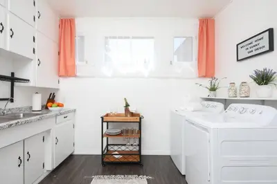 a white kitchen with white cabinets and orange curtains at 3 Bedroom 2 Bath House with Parking - 10 Guests in San Diego