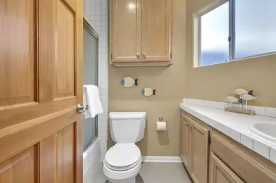 a bathroom with a toilet and a sink and a window at Pine Street #2 in Oceanside