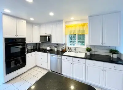 a white kitchen with white cabinets and a black appliances at 4 Bedroom 2 Bath with Ocean View Hot Tub Parking in San Diego