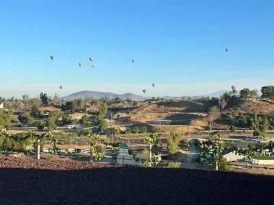 a group of hot air balloons flying over a town at An Architectural masterpiece with unparalleled beauty, elegance and amenities in Temecula