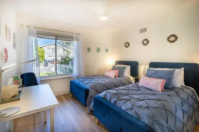 a bedroom with two beds and a desk and a window at Stunning 4 Bedroom 1 Level- Pool, Spa, Grass Yard, Fire Pit, Garage, BBQ in Mission Viejo